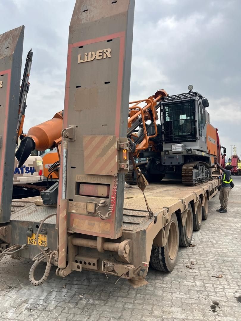 Orange crawler drilling rig secured on a Lider lowbed trailer, with a crew member checking the load