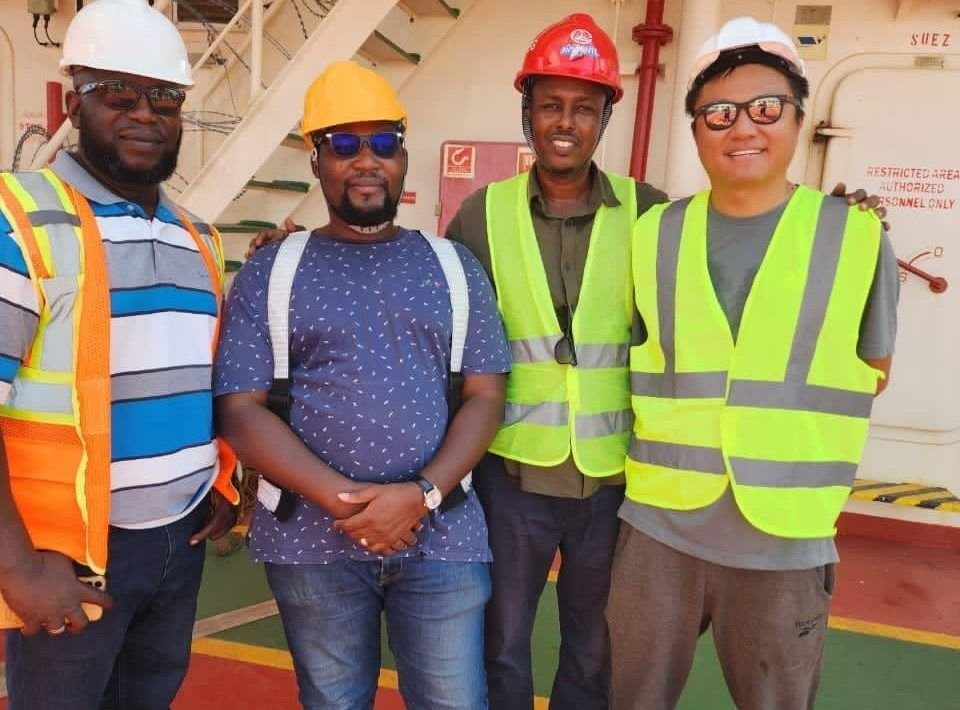 Four Transit Cargo Limited staff in hard hats and vests on board a vessel