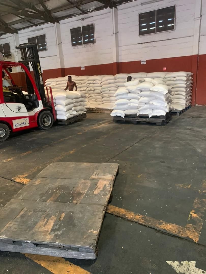 Forklift moving pallets of white sacks inside a warehouse